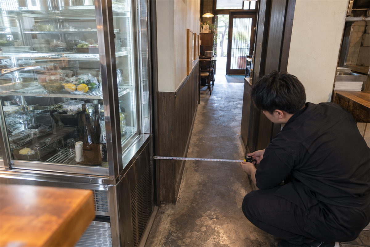 冷蔵ショーケースから店舗出口までの搬出経路を採寸する様子